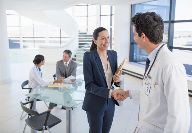 Doctor shaking hands with woman in business suite